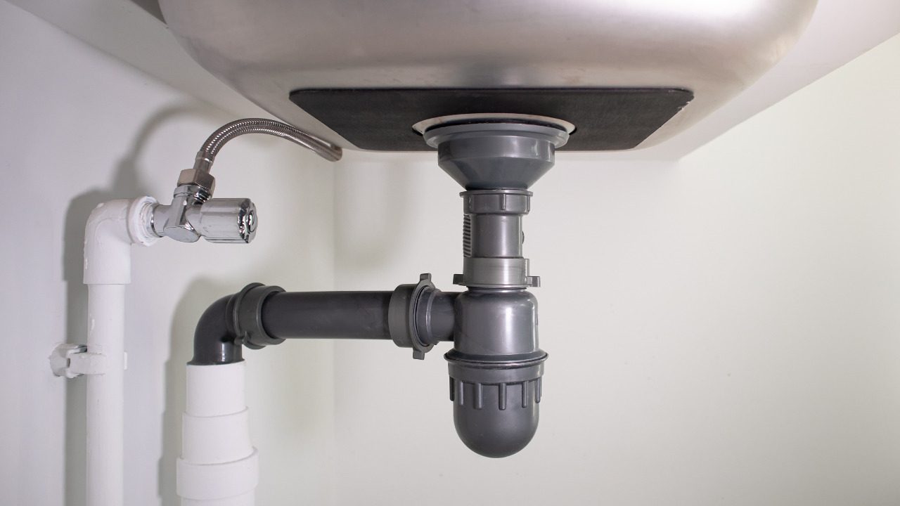 Drain pipes and a P-trap connected beneath a kitchen sink
